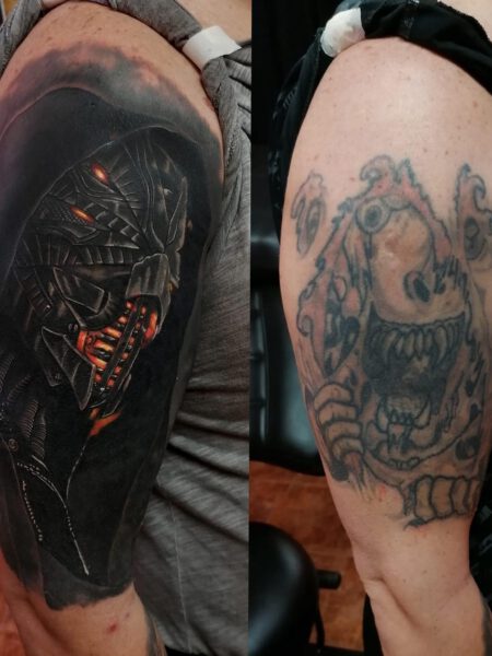 Cover Up Tätowierung - Alte Tätowierung auf dem Oberarm einer Frau. Neues Tattoo zeigt einen mystischen Mann mit Maske auf dunklem Hintergrund.