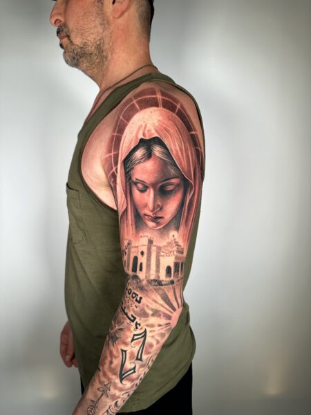 Chicano Tattoo Stil, Tätowierung auf dem Oberarm eines Mannes, schwarz-weißes Tattoo zeigt eine Frau mit einem Tuch um den Kopf gewickelt