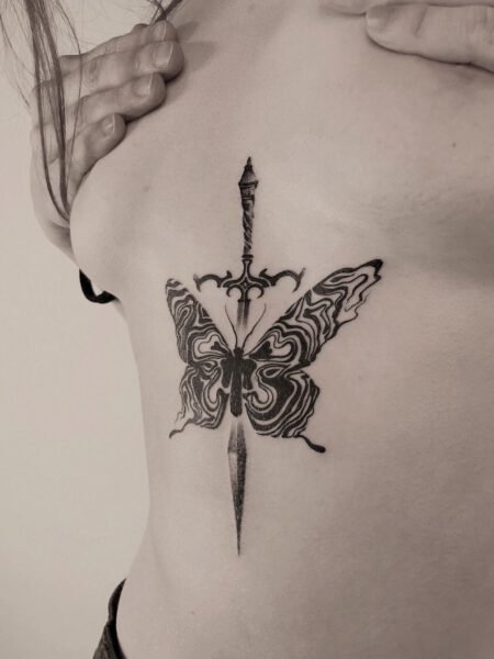 Black & Grey Tattoostil Schmetterling mit Schwert unter der Brust einer Frau